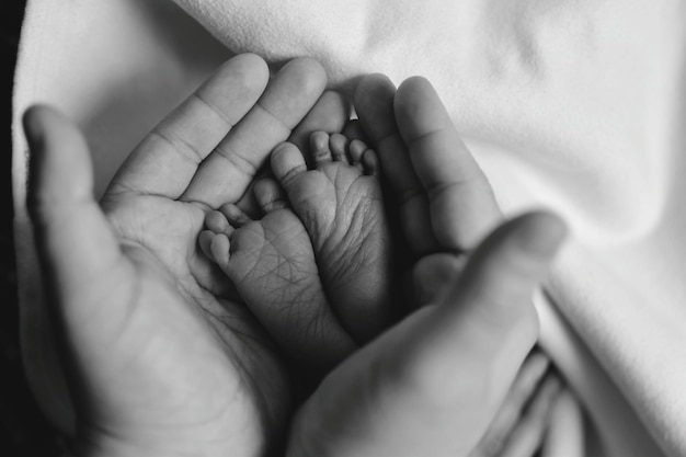 赤ちゃんの足を握っている親のカットされた画像