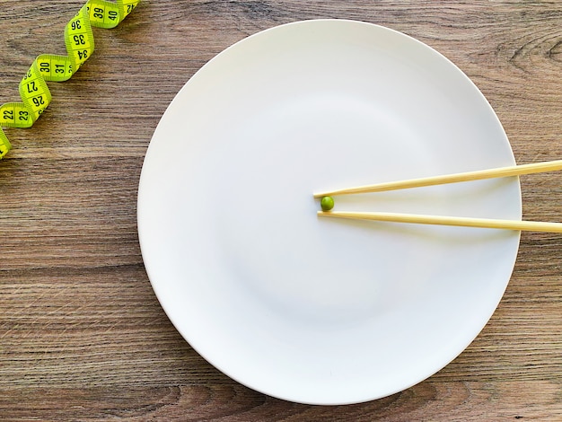 Cropped image pea on white plate, with fork and measuring