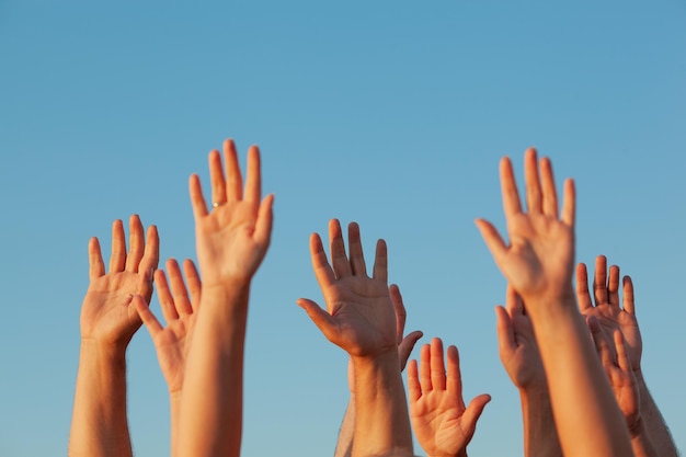 Photo cropped image of people with arms raised against clear sky