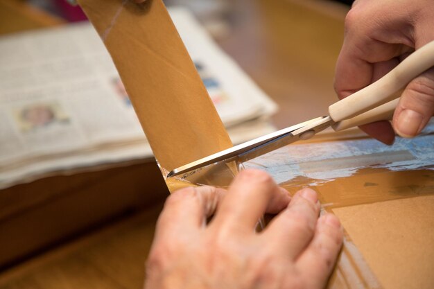 Photo cropped image of person cutting adhesive tape with scissors