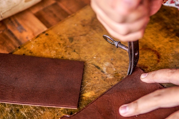 cropped image of person cutting leather on table