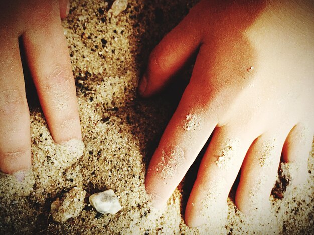 Cropped image of person hand on sand at beach