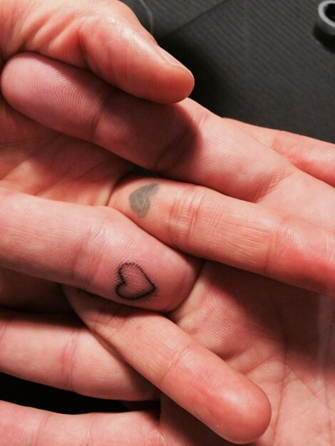 Cropped image of person hands with heart shape tattoo