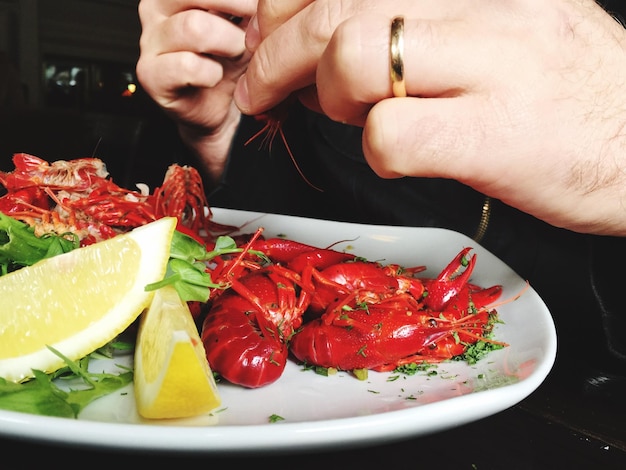 Foto immagine ritagliata di una persona che mangia gamberetti in un ristorante