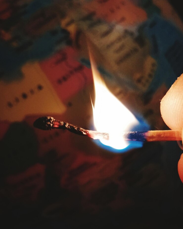 Photo cropped image of person holding burning matchstick