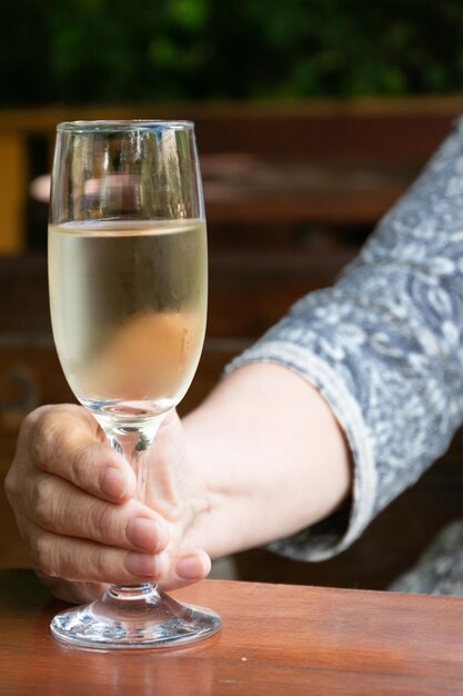 Photo cropped image of person holding glass of wineglass on table