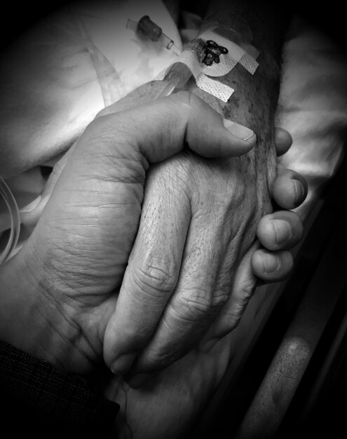 Cropped image of person holding patient hand in hospital