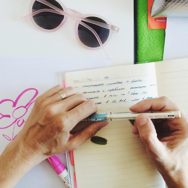 Cropped image of person holding pen on diary