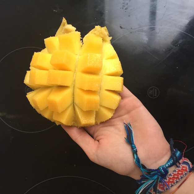 Cropped image of person holding sliced mango