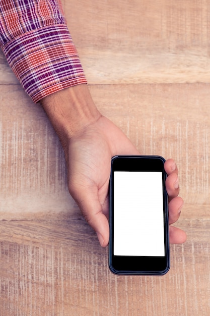 Cropped image of person holding smart phone on desk