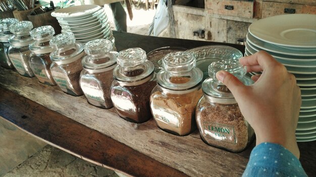 Photo cropped image of person holding tea jar on wooden table