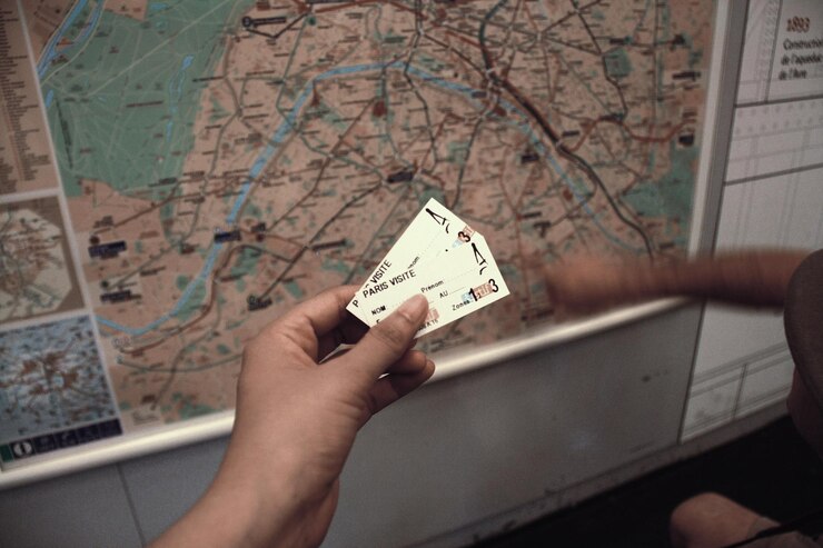 Фотография обрезка изображения человека, держащего билет на поезд, напротив карты на станции