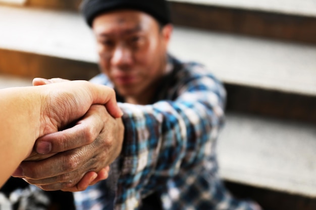 Photo cropped image of person shaking hand with beggar