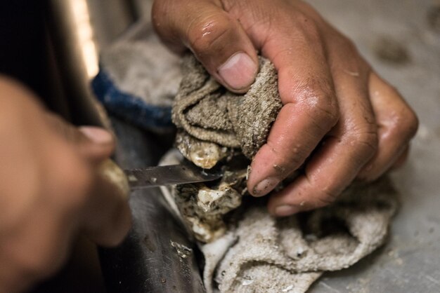 Cropped image of person shucking oyster on table