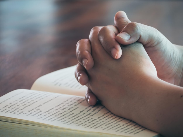 Photo cropped image of person with hands clasped on book