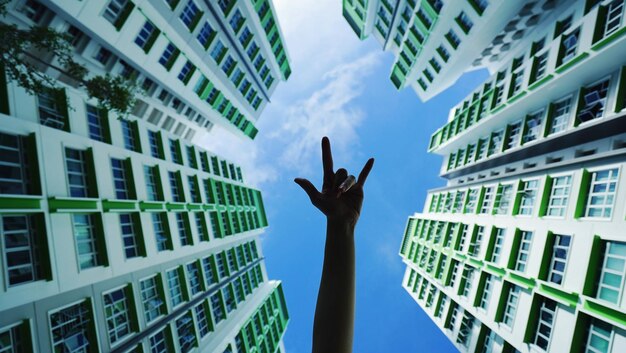 Foto immagine ritagliata di una persona con un cartello di musica rock tra gli edifici contro il cielo