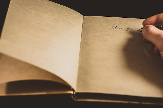 cropped image of person writing in book against black background