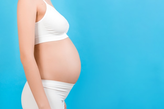 Cropped image of pregnant woman's abdomen at blue