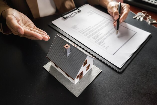 Photo cropped image of real estate agent gesturing at model home on table