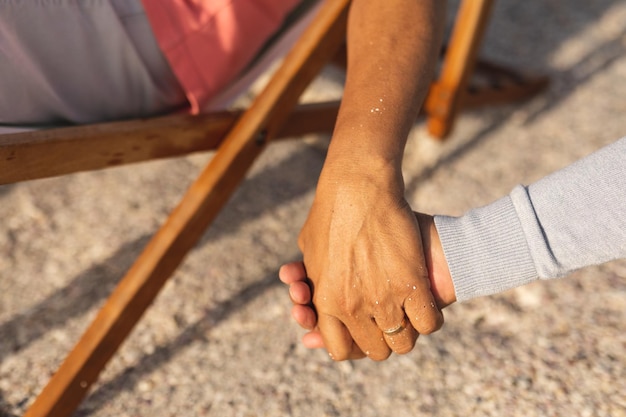 Foto immagine ritagliata di una coppia multirazziale senior che si tiene per mano mentre si gode la pensione in spiaggia