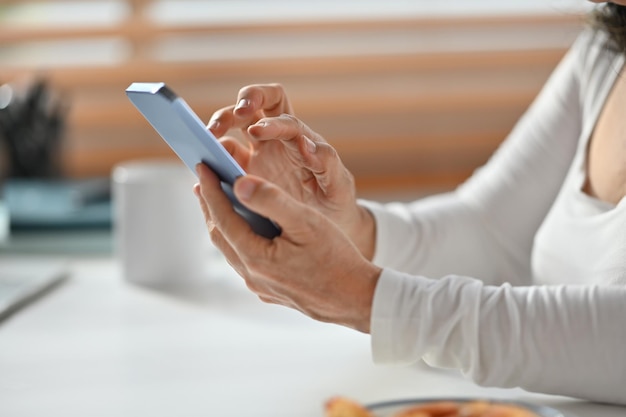 Photo cropped image of senior woman hand texting messages enjoying chatting in social on smartphone