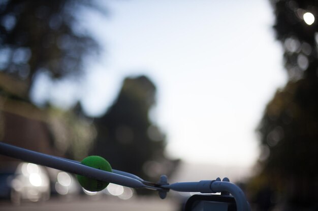 Photo cropped image of side-view mirror with tennis ball against sky