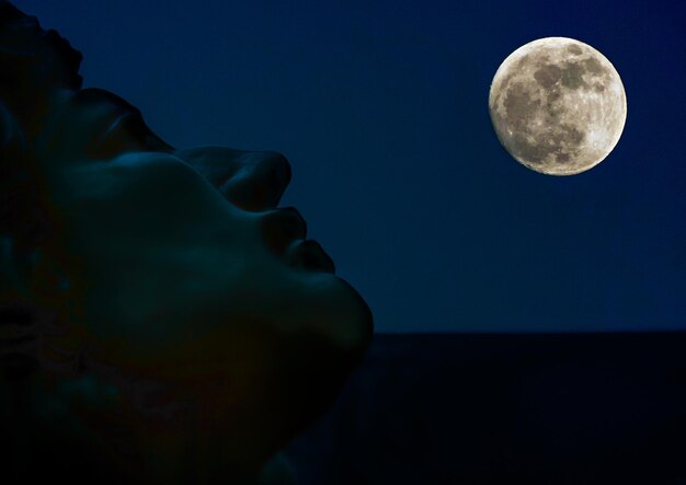 Foto immagine ritagliata della statua contro la luna piena di notte