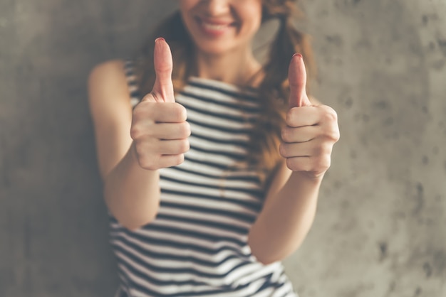 Photo cropped image of stylish young woman showing thumbs