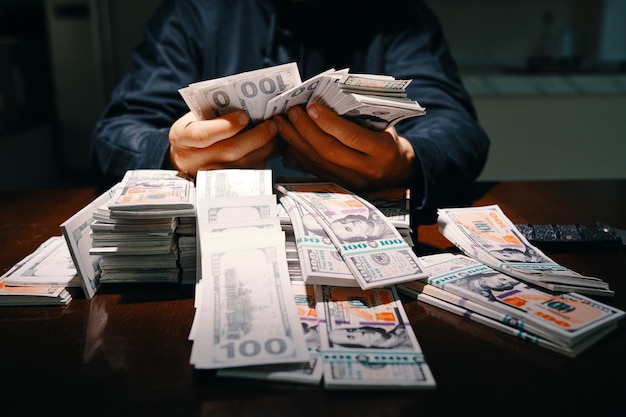 Cropped image of thief counting stolen money on table in front of him