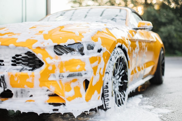 Cropped image of wheel of luxury yellow car in outdoors selfservice car wash