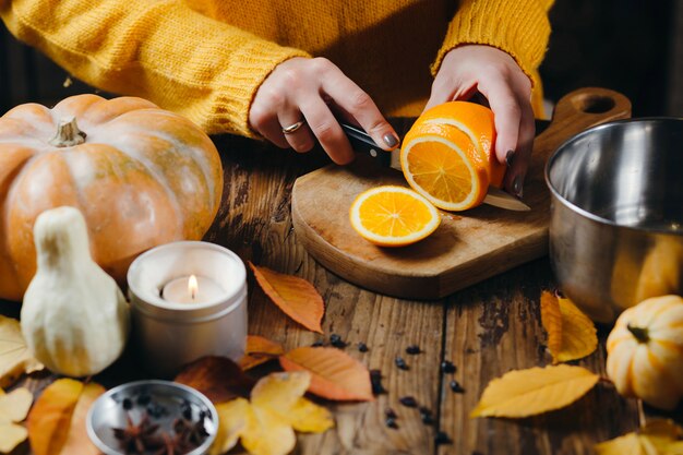 Photo cropped image of woman cutting fruits for mulled win