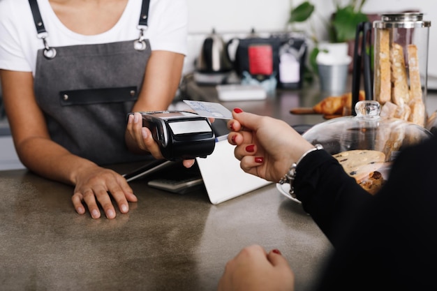 Photo cropped image of woman hand holding credit card while making payment in cafe