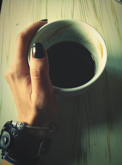 Foto immagine ritagliata di una mano di donna con il caffè al tavolo