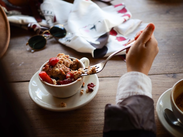 Photo cropped image of woman having rice pudding at wooden table