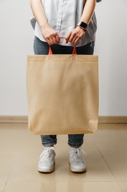 Cropped image of woman holding beige shopping bag in studio