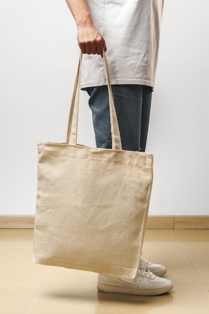 Cropped image of woman holding beige shopping bag in studio