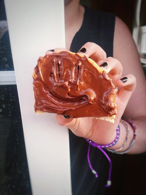 Foto immagine ritagliata di una donna che tiene il pane con il cioccolato