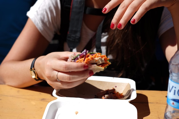 Photo cropped image of woman holding chicken wrap sandwich