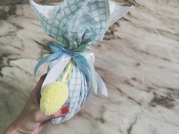 Cropped image of woman holding decorative gift over marble