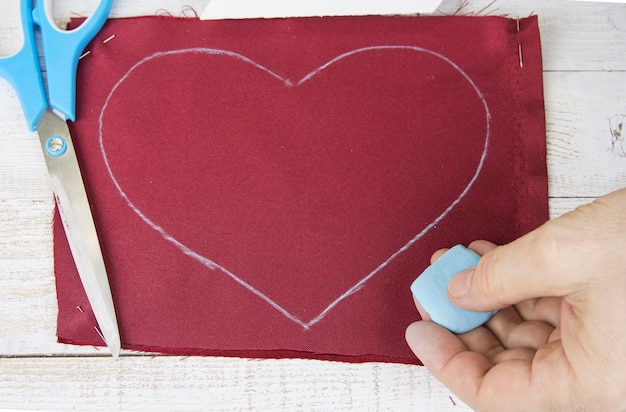 Foto immagine ritagliata di una donna che tiene un foglio a forma di cuore sul tavolo