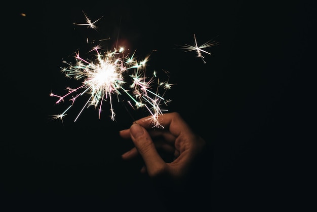 Photo cropped image of woman holding sparkler against black background