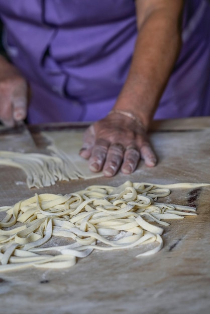 Foto immagine ritagliata di una donna che prepara la pasta sul tavolo in cucina a casa