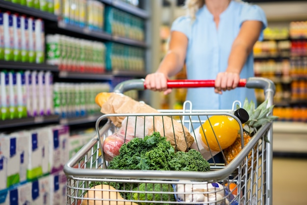 cropped image of woman pushing trolley in aisle 