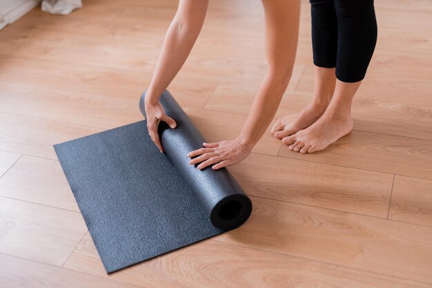 Photo cropped image of woman rolling yoga mat