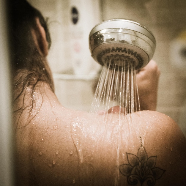 Foto immagine ritagliata di una donna che fa la doccia in bagno
