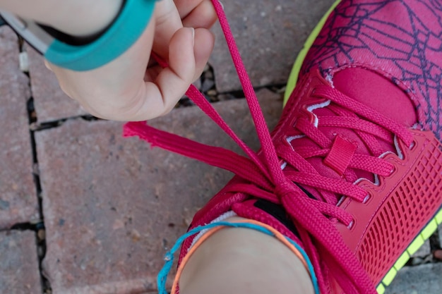 Foto immagine ritagliata di una donna che lega i lacci delle scarpe sul marciapiede