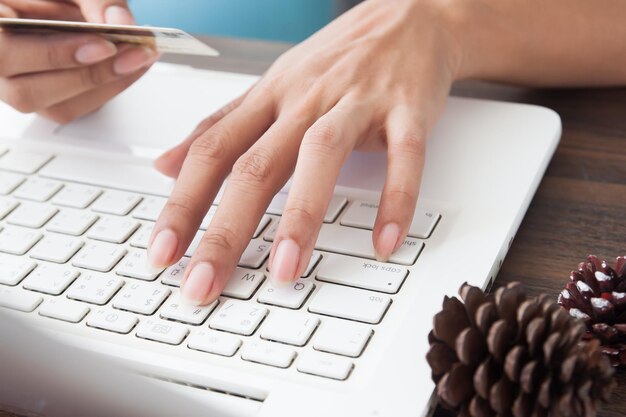 Cropped image of woman using credit card and laptop