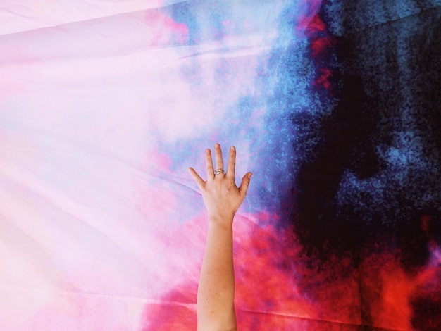 cropped image of woman with hand raised against textile