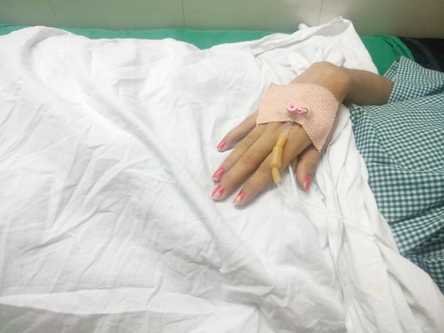 Foto immagine ritagliata di una donna con una flebo a goccia in mano in ospedale