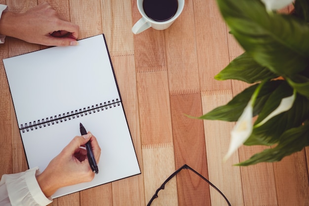 Cropped image of woman writing on notepad